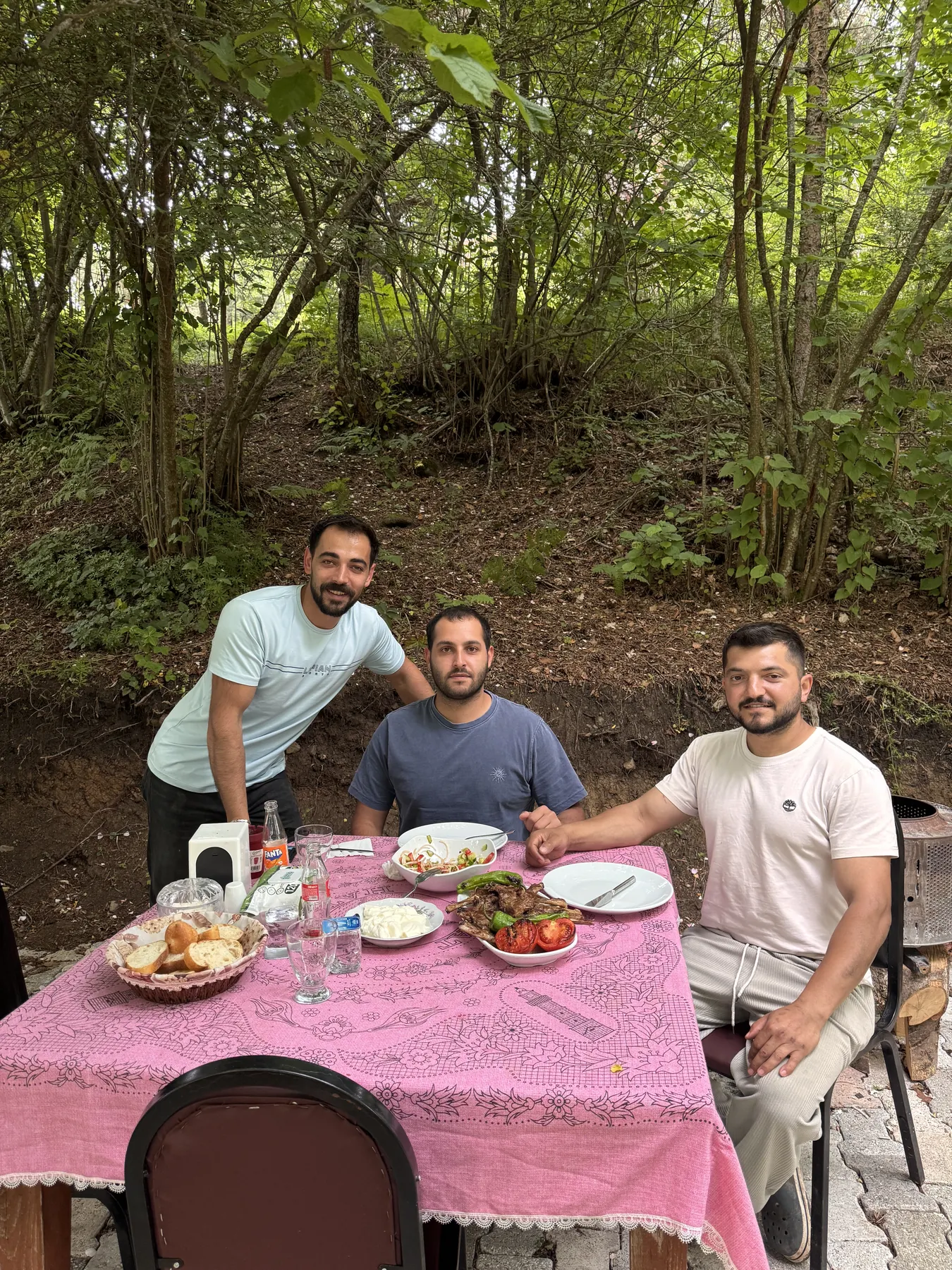 Ağaçların altında kurulan mangal sofrasında misafirler